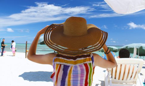 ビーチで大きな帽子をかぶる女性